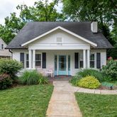 a view of house with a yard and potted plants