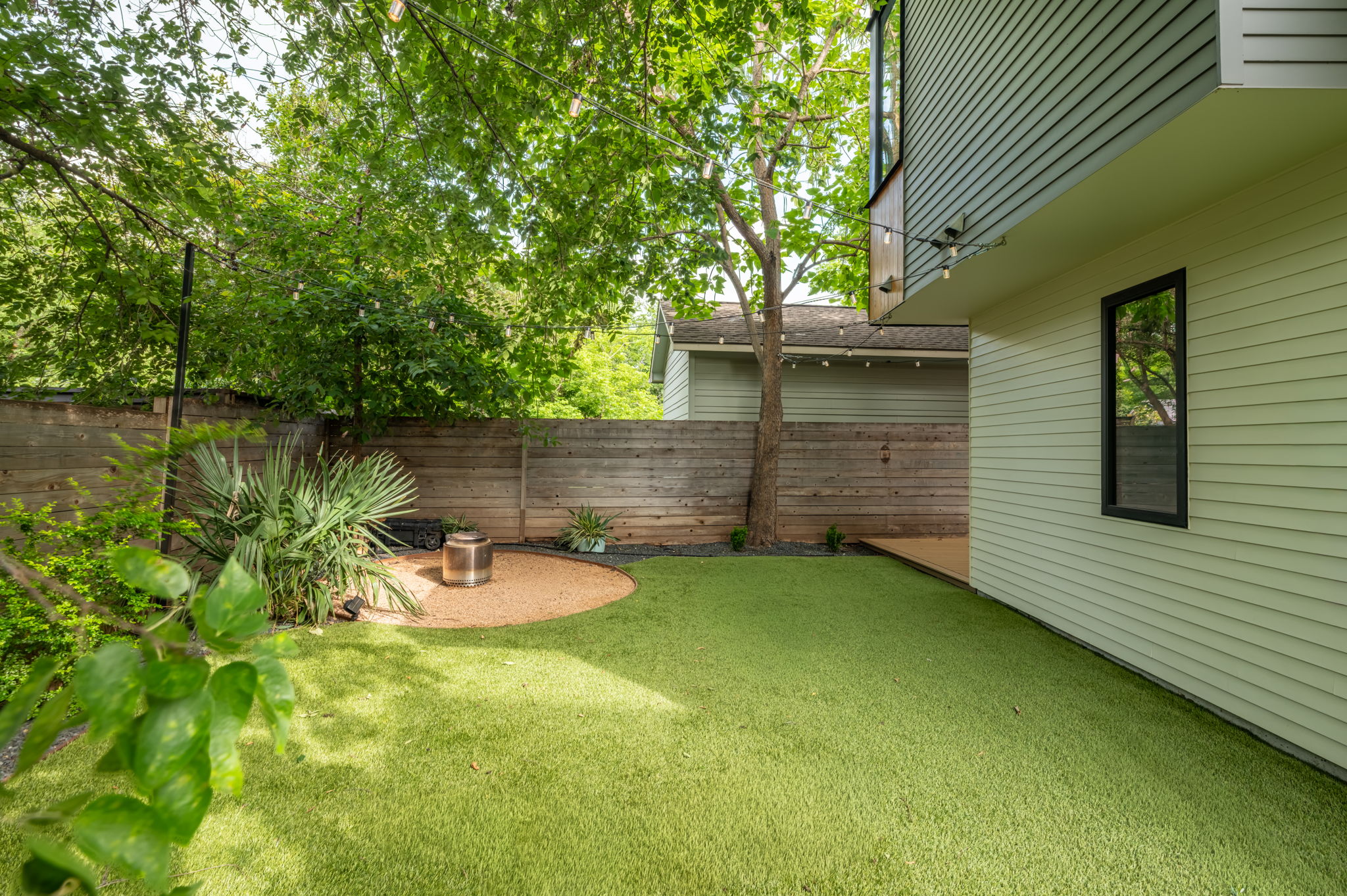 1811 Collier Street Austin, TX 78704 - Photo 36 of 40 Artificial turf lawn with a circular gravel patio featuring a fire pit