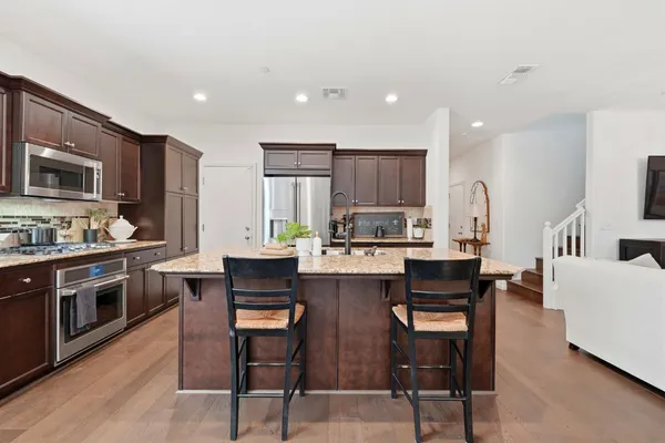 a kitchen with stainless steel appliances granite countertop a sink refrigerator and cabinets