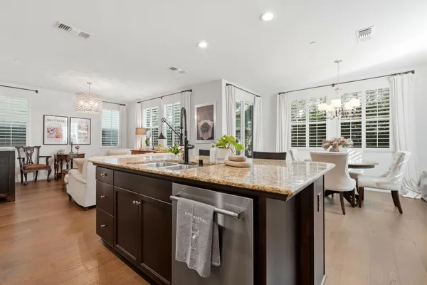 a dining room with wooden floor a chandelier a glass table and chairs
