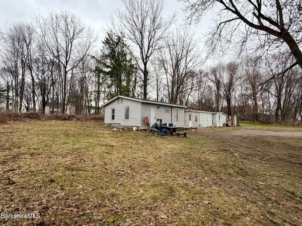 a view of a house with a yard covered with snow and trees