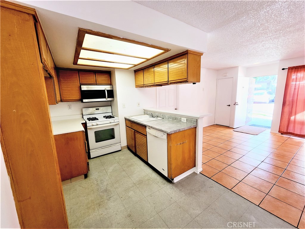 12601 Van Nuys Boulevard, Unit 138 Pacoima, CA 91331 - Photo 8 of 19 a kitchen with stainless steel appliances granite countertop a stove a sink and a microwave