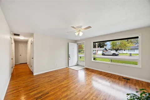 a view of an empty room with window and wooden floor