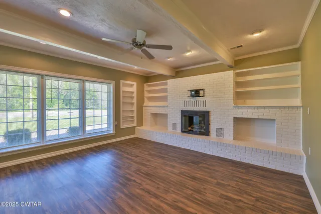a view of an empty room with a fireplace and a window