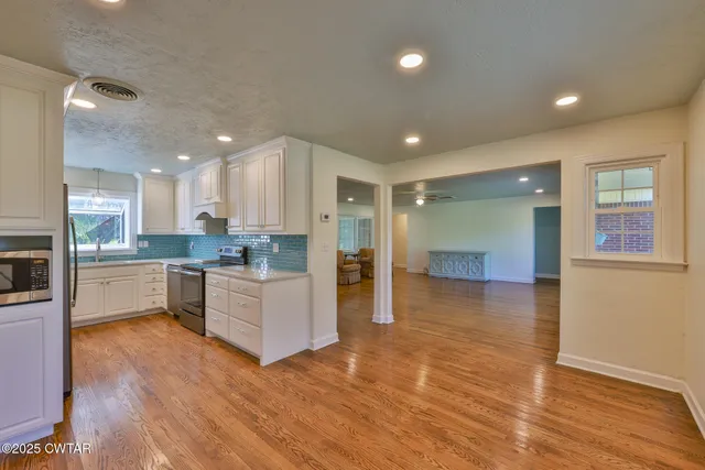 a large kitchen with stainless steel appliances granite countertop a large counter top a sink and a refrigerator