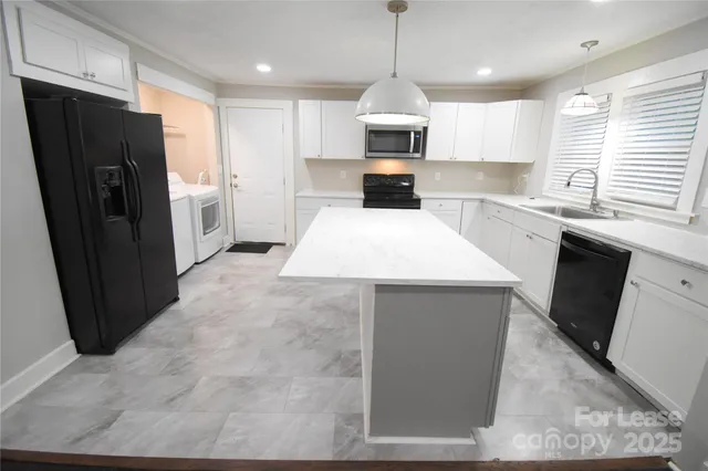 a large kitchen with stainless steel appliances kitchen island granite countertop a refrigerator a sink a stove a microwave and island