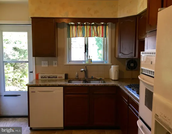 a kitchen with granite countertop a sink a window stainless steel appliances and cabinets
