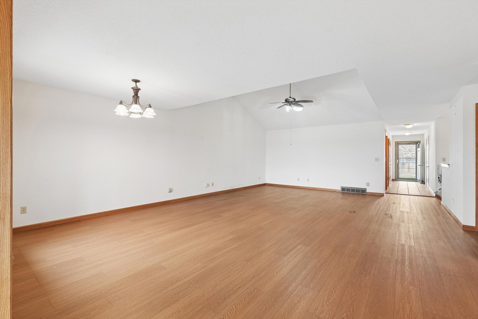 118 5th Street, Unit 2 Fulton, IL 61252 - Photo 5 of 54 an empty room with a chandelier fan and wooden floor