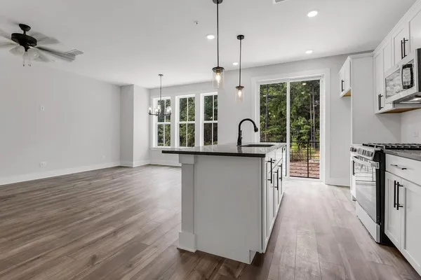 a kitchen with stainless steel appliances granite countertop a stove a sink a refrigerator and wooden floor