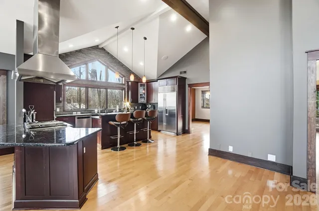 a kitchen with stainless steel appliances kitchen island granite countertop a refrigerator a sink a stove and a wooden floors