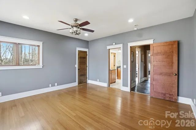 a view of an empty room with window and wooden floor