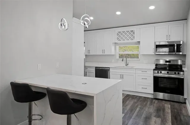 a kitchen with granite countertop a stove a sink and a microwave