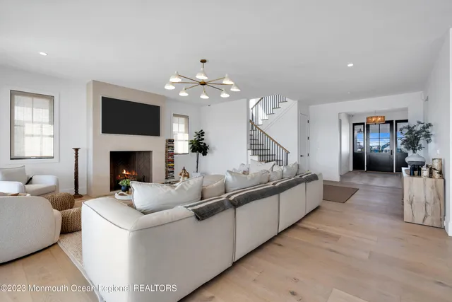 a large kitchen with kitchen island a large counter top space a sink a stove and a view of living room