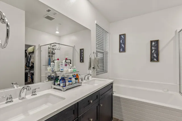 a bathroom with a granite countertop sink double vanity granite tub shower and a mirror