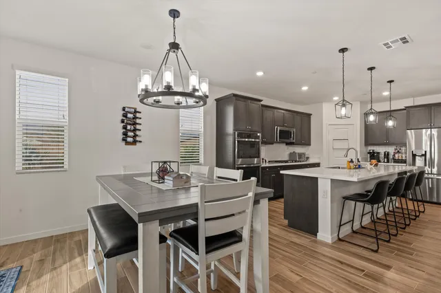 a kitchen with stainless steel appliances granite countertop a dining table chairs stove a refrigerator and a window