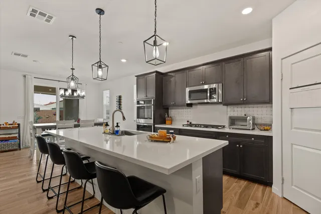 a kitchen with stainless steel appliances a stove a sink a microwave a center island and cabinets