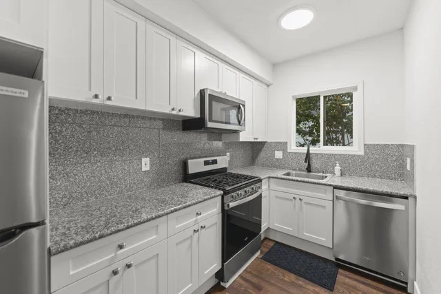 a kitchen with stainless steel appliances granite countertop a sink stove and cabinets