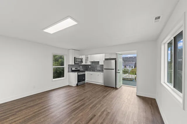 a kitchen with stainless steel appliances wooden floors and white walls