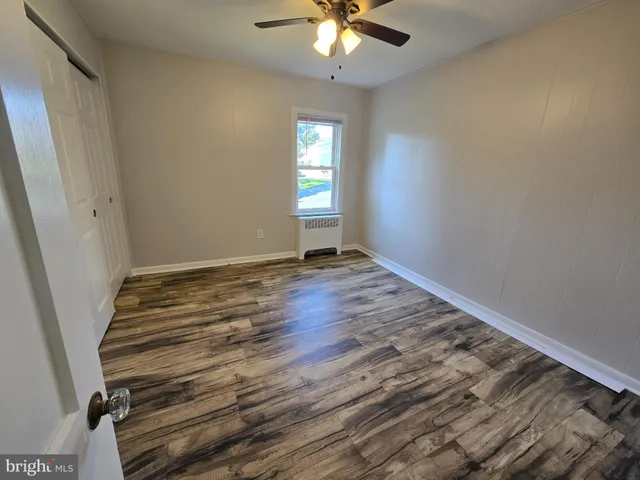 a view of an empty room with window and wooden floor