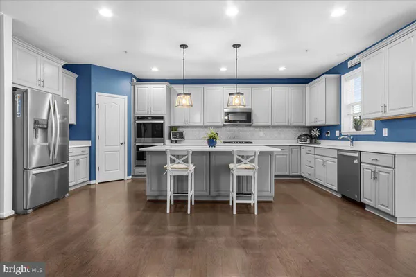 a kitchen with stainless steel appliances kitchen island granite countertop a table chairs refrigerator and microwave