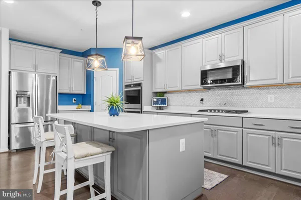 a kitchen with stainless steel appliances a stove a sink a microwave a refrigerator and white cabinets