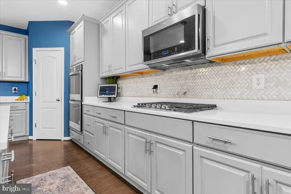 a kitchen with stainless steel appliances white cabinets and a wooden floor