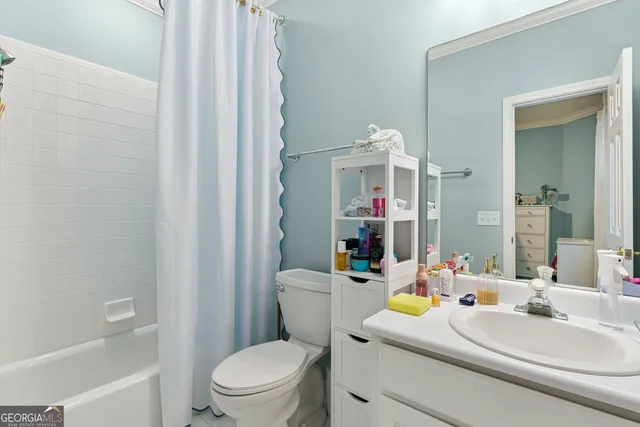 a bathroom with a sink a toilet a mirror and shower curtain