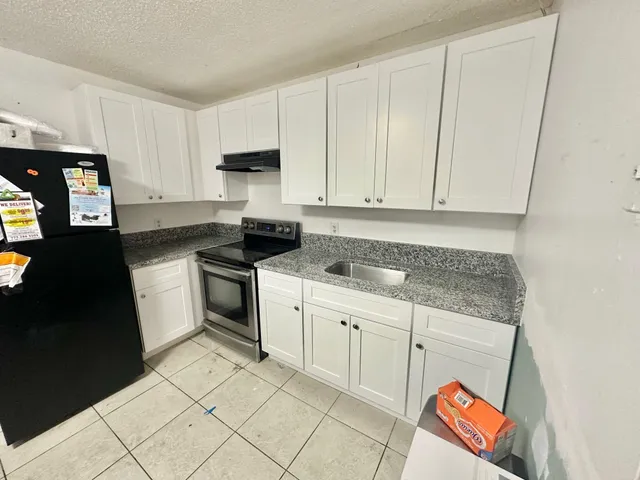 a kitchen with granite countertop white cabinets and black appliances