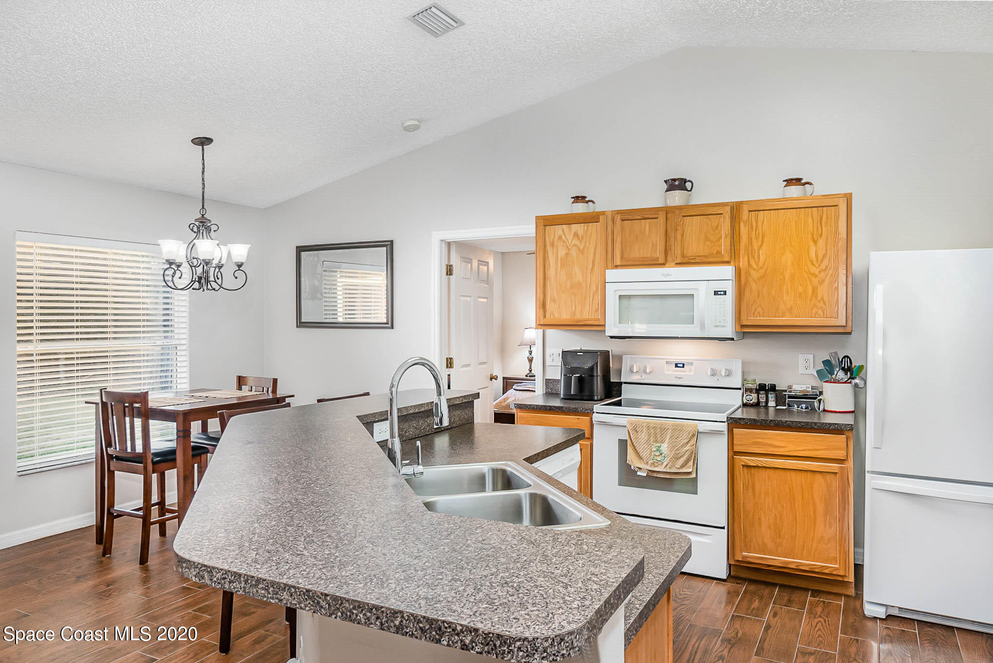 5209 Carrick Road Cocoa, FL 32927 - Photo 7 of 23 a kitchen with granite countertop a stove a sink a dining table and chairs with wooden floor