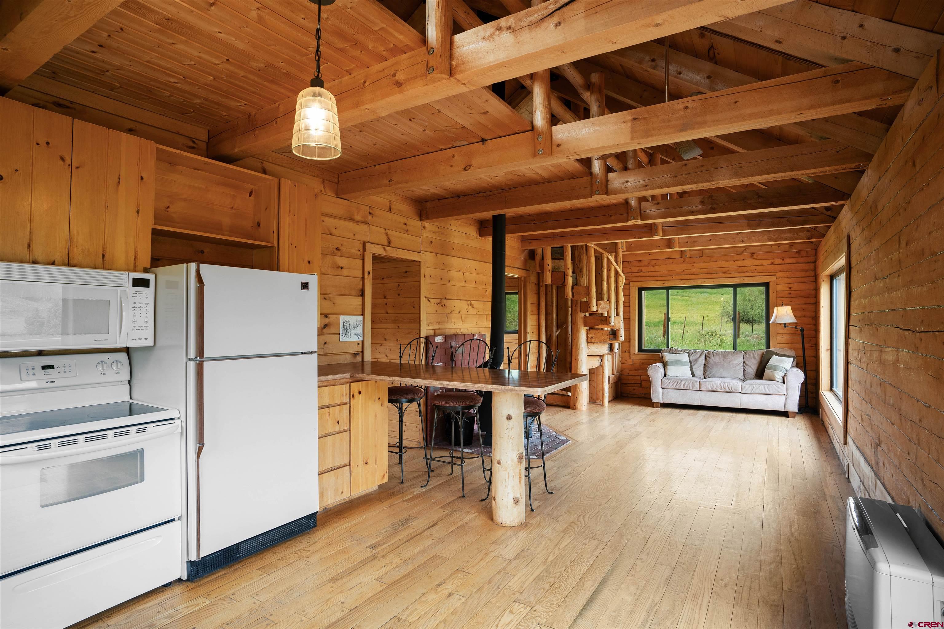 320 Sioux Road Gunnison, CO 81230 - Photo 6 of 35 a kitchen with stainless steel appliances a stove a refrigerator a dining table and chairs with wooden floor
