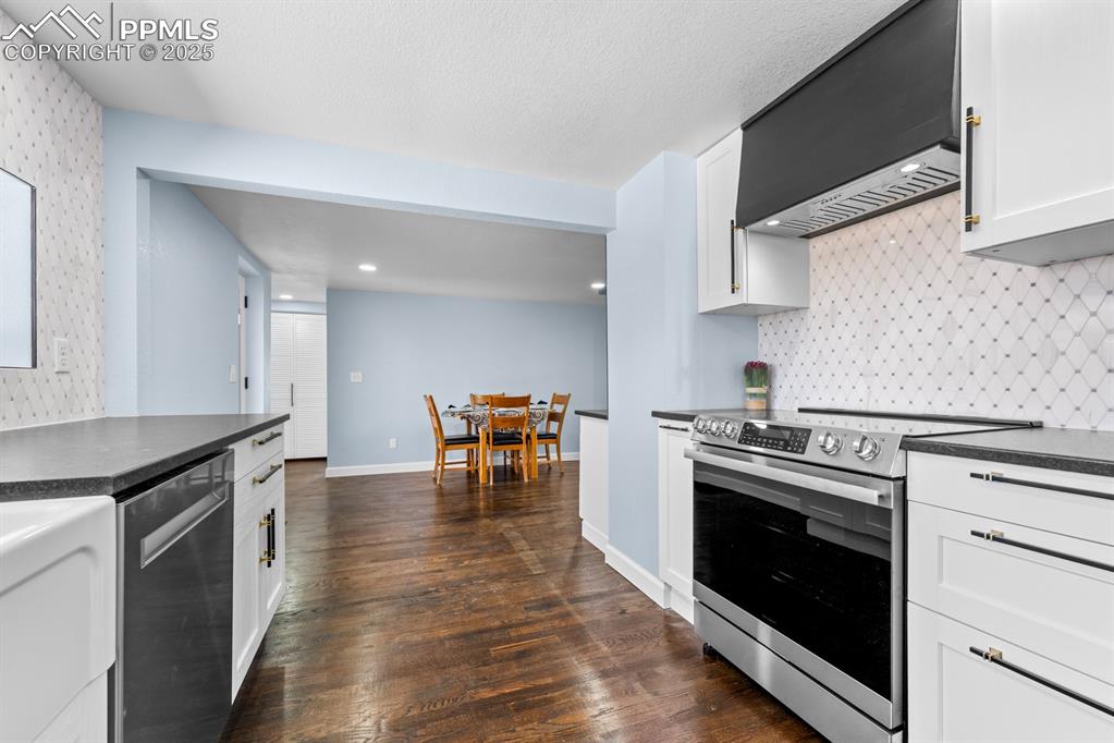 29767 Preston Road Pueblo, CO 81006 - Photo 14 of 46 a kitchen with granite countertop a stove top oven a sink dishwasher and white cabinets with wooden floor