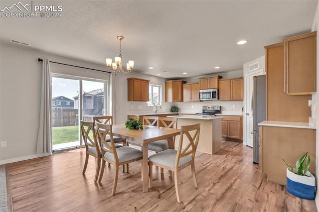 11053 Avena Road Peyton, CO 80831 - Photo 6 of 27 Dining space featuring light wood finished floors, a chandelier, recessed lighting, and plenty of natural light