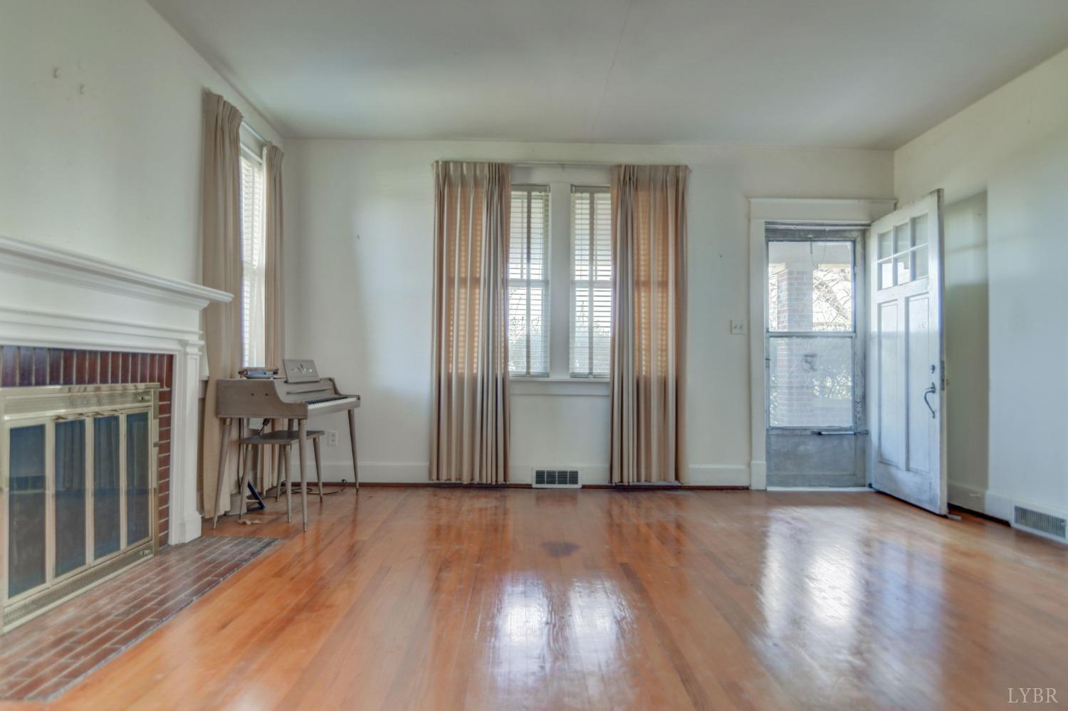 231 Epsons Road Long Island, VA 24569 - Photo 3 of 38 an empty room with wooden floor and a fireplace