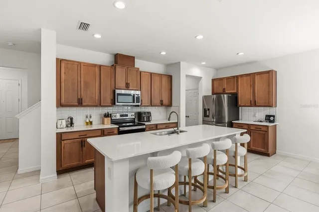 a kitchen with stainless steel appliances granite countertop a table chairs sink refrigerator and cabinets