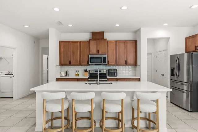 a kitchen with stainless steel appliances granite countertop a table chairs refrigerator and microwave