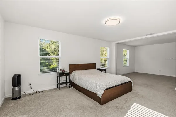 a bedroom with a bed a table and windows