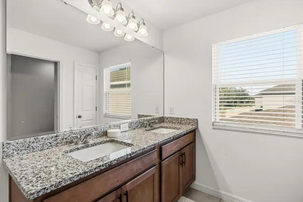 a bathroom with a granite countertop sink and a large mirror