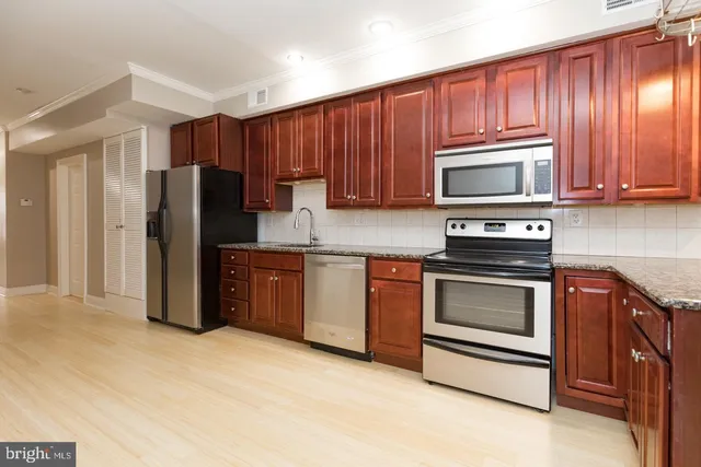 a kitchen with granite countertop wooden cabinets stainless steel appliances and a window
