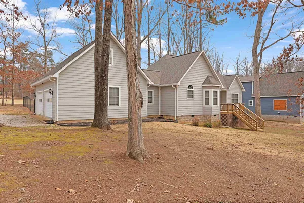 a front view of a house with a dirt yard and a large tree