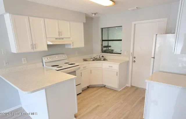 a kitchen with a sink a stove a refrigerator and white cabinets