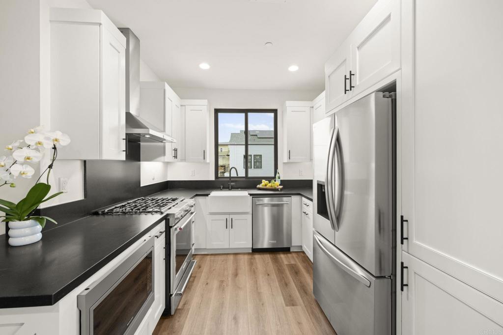 1303 Bergamo, Unit 201 Encinitas, CA 92024 - Photo 6 of 42 a kitchen with stainless steel appliances granite countertop a refrigerator a sink dishwasher a stove and white countertops with wooden floor
