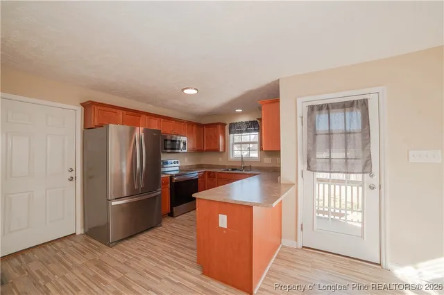 a kitchen with stainless steel appliances granite countertop a refrigerator a sink a stove and wooden floor