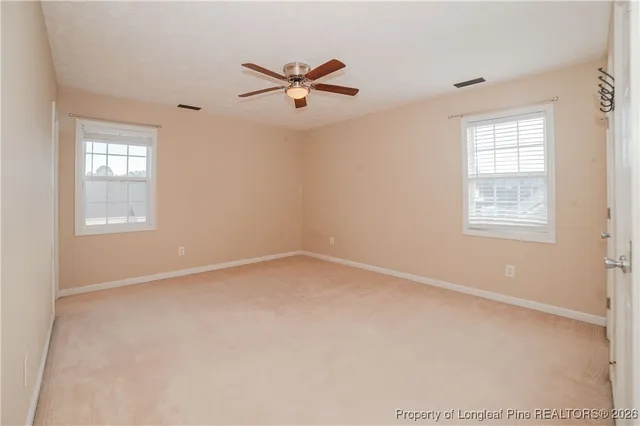 an empty room with windows and fan
