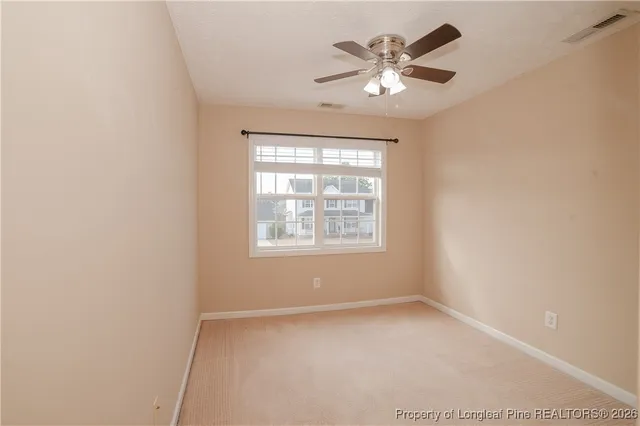an empty room with windows and chandelier fan