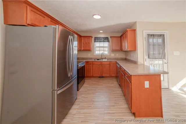 a kitchen with stainless steel appliances granite countertop a refrigerator a sink dishwasher a stove with wooden cabinets and floor