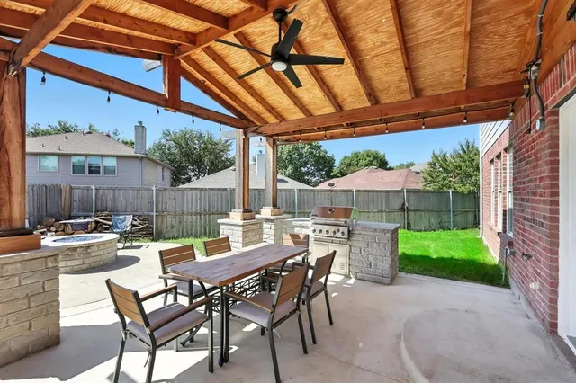 a view of a patio with a table and chairs under an umbrella with a small yard