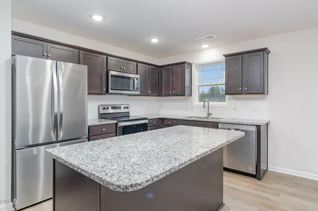 a kitchen with stainless steel appliances granite countertop a sink stove and refrigerator