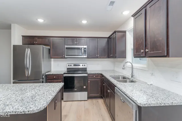 a kitchen with stainless steel appliances granite countertop a sink stove microwave and refrigerator