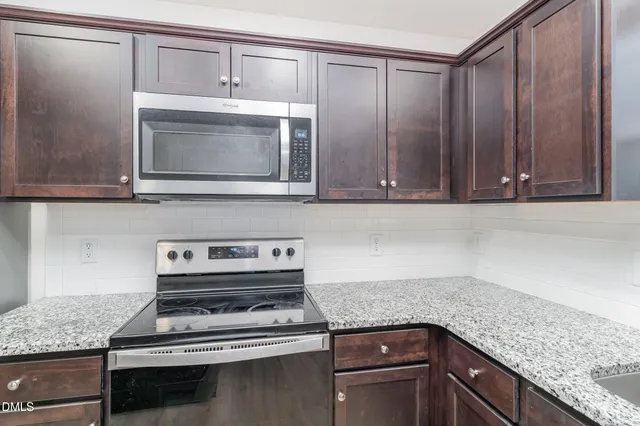 a kitchen with granite countertop cabinets stainless steel appliances and a counter space