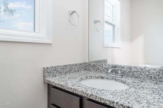 a bathroom with a granite countertop sink and a mirror